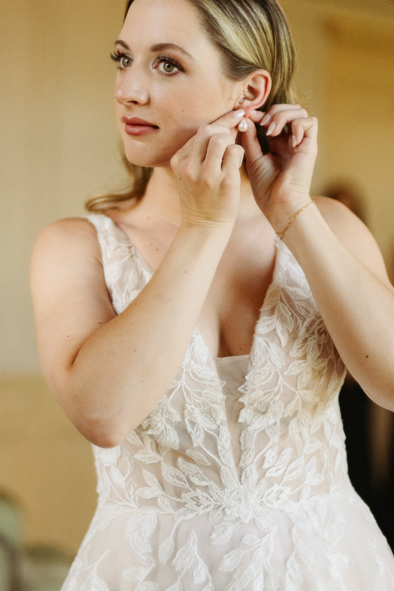 Bride fastening pearl earring while getting ready with Doorbell Salon in Connecticut